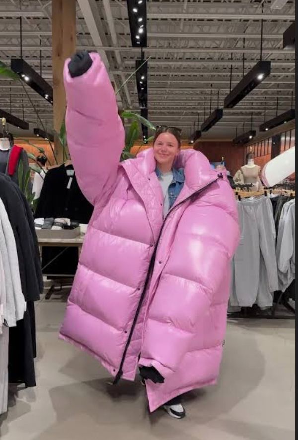 A woman wearing a comically oversized pink puffer jacket 