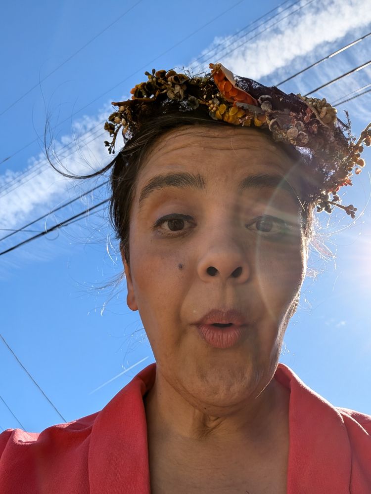 Image of a brown Latina in period 1940's attire making a face with blue sky and a cloud streak behind her. 