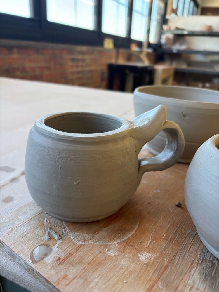 Unfired clay mug on wooden tray