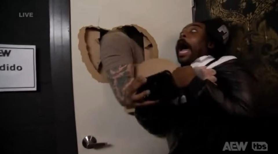 Wrestler Brody King’s arm punching through a door to choke a surprised Stokely 