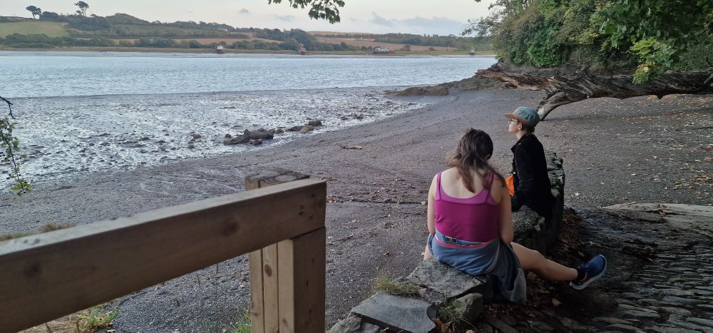 Two kids sitting on the wall looking out at the estuary 