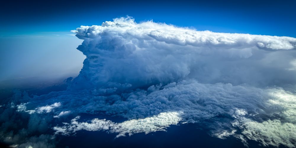 A large cumulonimbus with a spreading anvil top that looks like the profile of an angry Greek god with curly hair and a billowing beard 