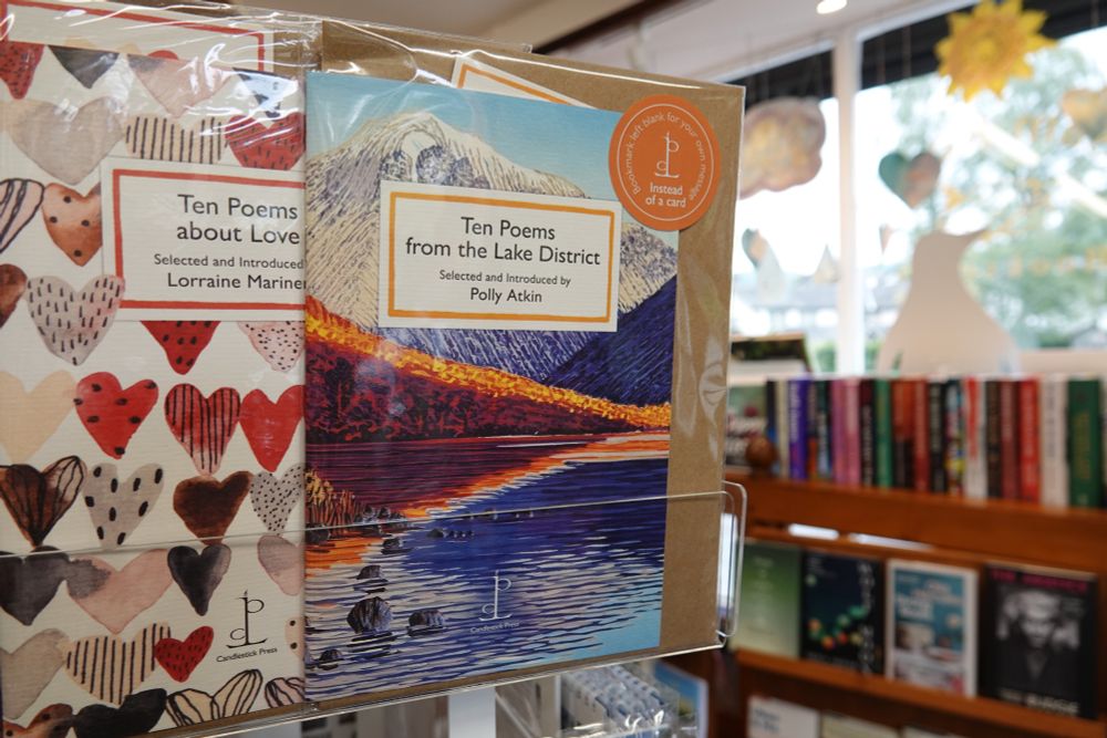 Ten Poems from the Lake District, selected and introduced by Polly Atkin on the bookshop spinner, alongside Lorraine Mariner (ed) Ten Poems about Love. Cut out penguin visible in the background in the bookshop window.