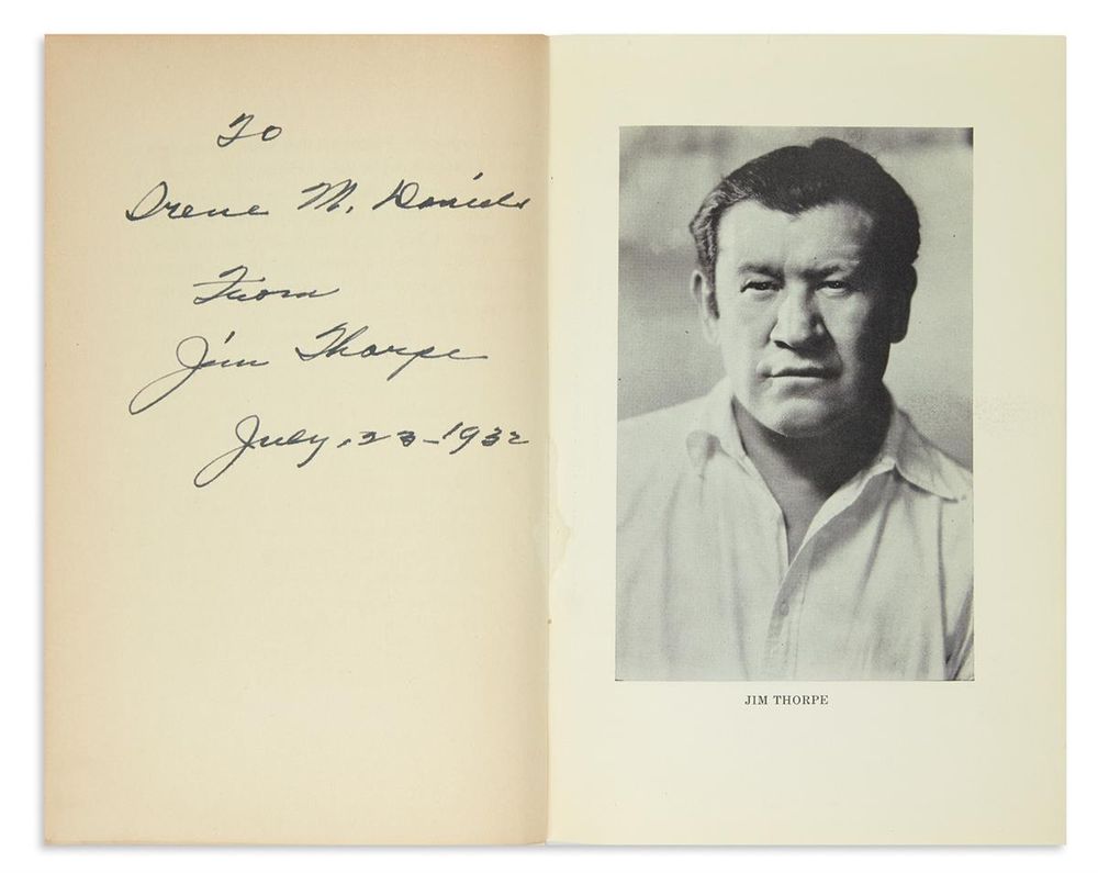Copy of Jim Thorpe's _History of the Olympics_ open to page showing his inscription on left side and portrait on the right.