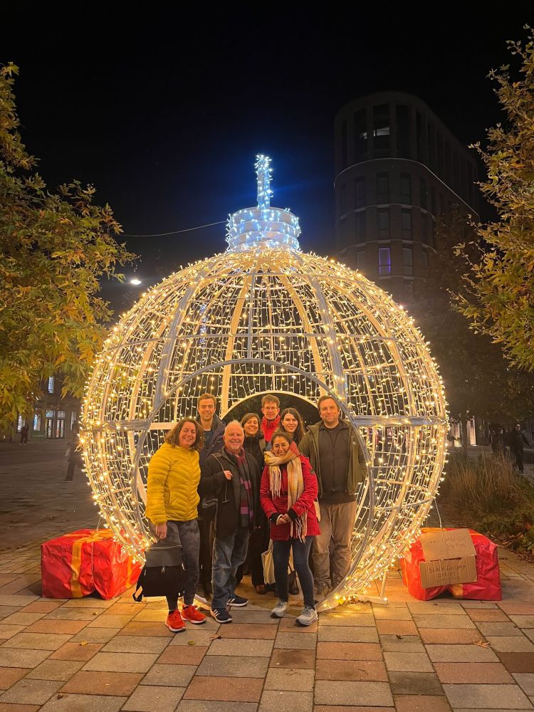 The PLOS Biology Staff Editors getting Christmas-y at the editorial retreat, standing in front of a giant lit up baubel!