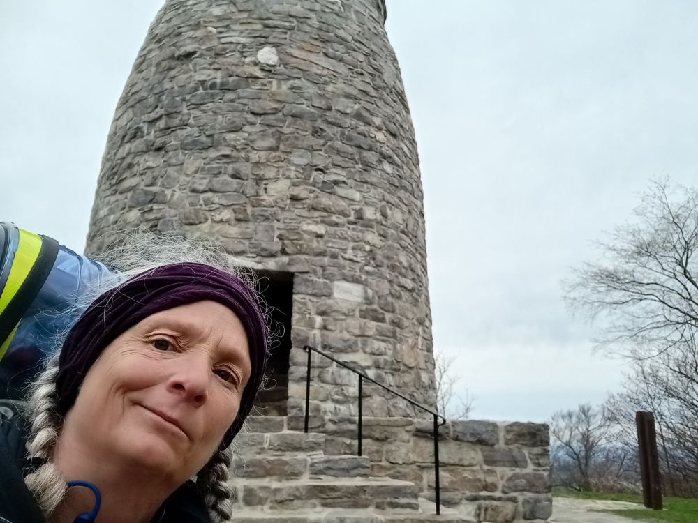 Picture of old white woman (me) in front of the original Washington Monument, located near Boonsboro, Maryland. Built by local residents in 1827. The Appalachian Trail goes past it. 