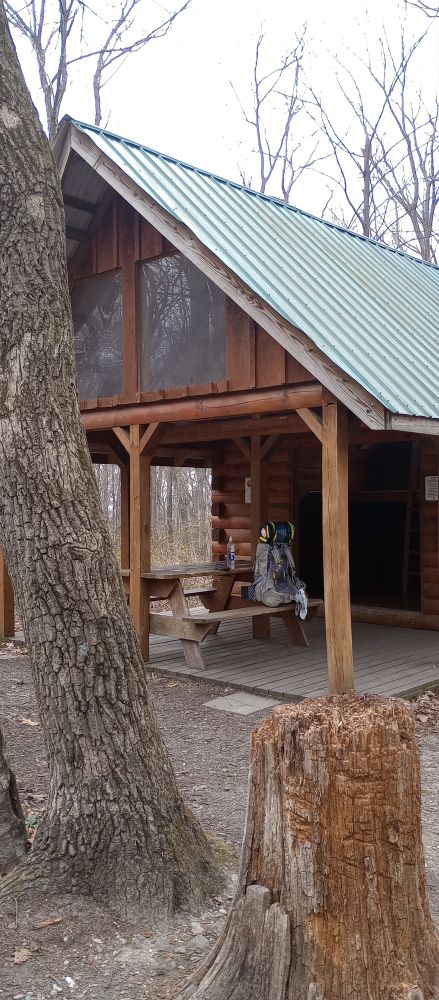 Grey backpack with bear canister on picnic table beneath overhang of a shelter along the Appalachian Trail.