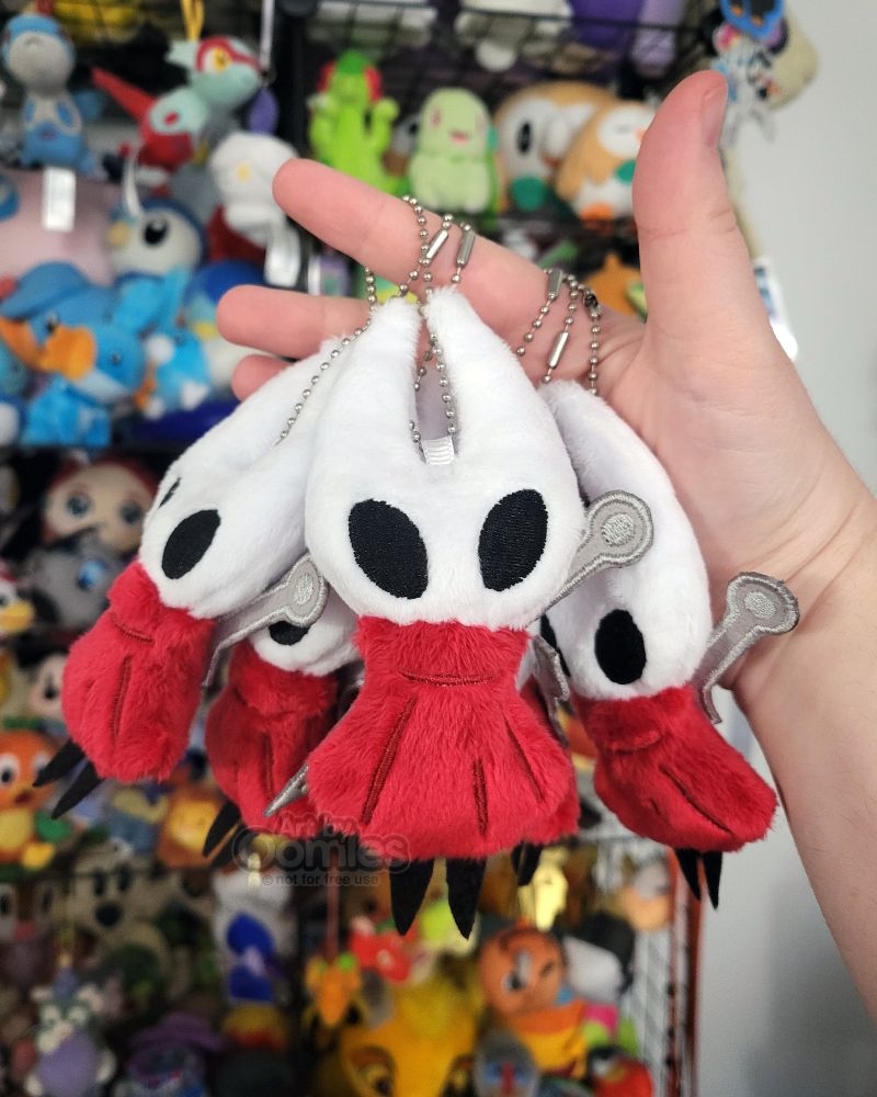 a photograph of multiple handmade plush charms of Hornet from Silksong made of minky and felt. They are about 5 inches tall and are being held my my hand.