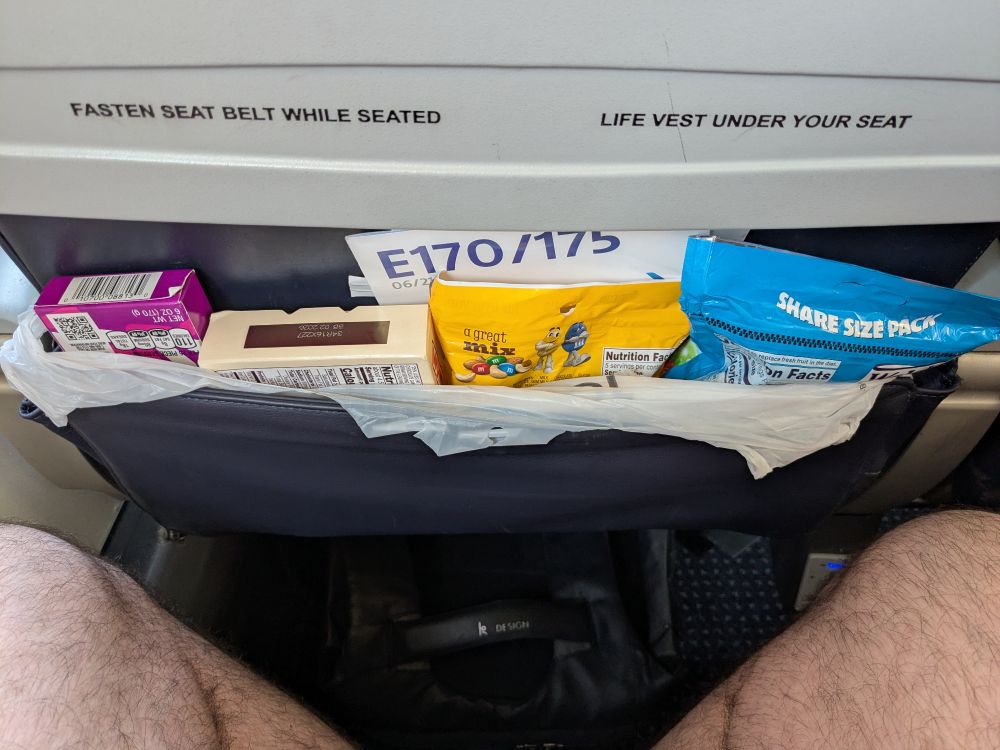 Several bags of candies for a two-hour flight, including Good & Plenty, Whoppers, peanut M&Ms, and fruit snacks