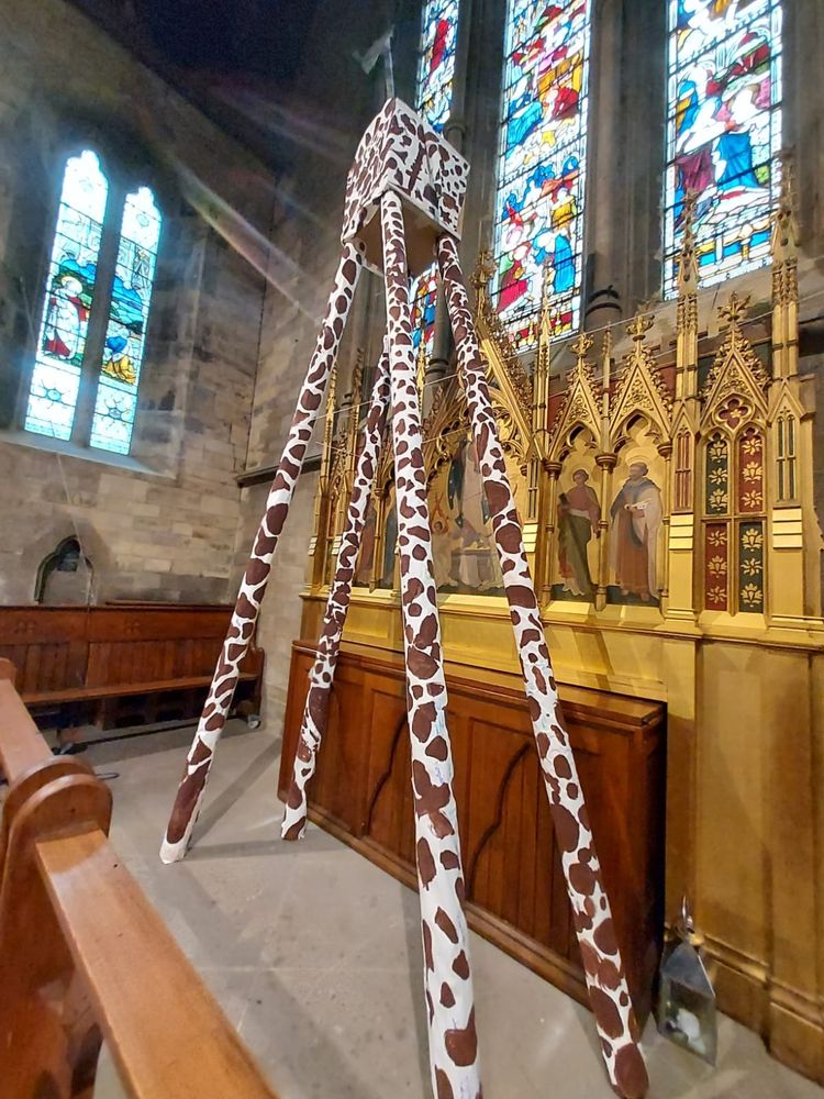 A 6 metre tall cardboard giraffe in a church.