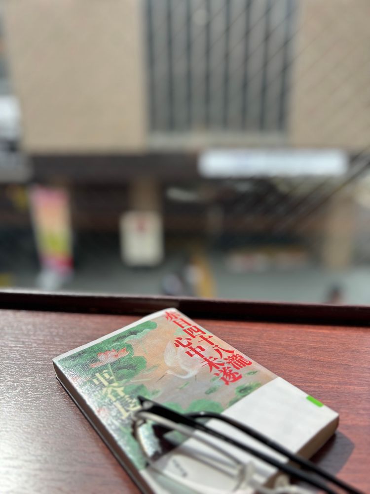 駅近の喫茶店2階の窓辺でぐんぐん読み進めていた時、少し休憩した時の写真。窓辺のカウンターの上に赤目四十八瀧心中未遂の文庫本とメガネが置いてある。