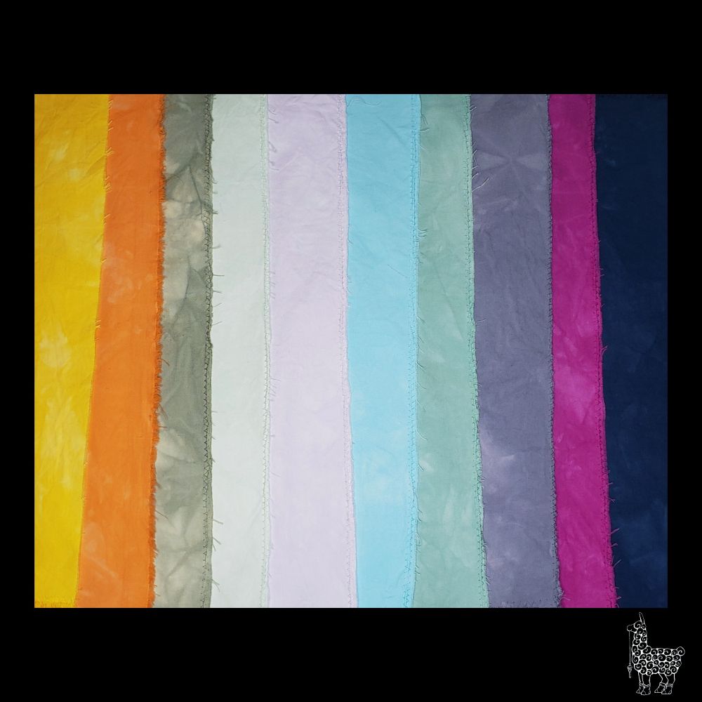An overhead photo of ten pieces of hand dyed fabric samples laid out overlapping each other so that a narrow band of each color of fabric is visible. The fabric has been machine zig zag stitched on the edges to reduce fraying. The fabrics have been scrunch dyed in low water immersion dyebaths to create color variation amd dimension. The photo has been cropped and a black border has been added. The Llady Llama logo is in the lower right corner.
