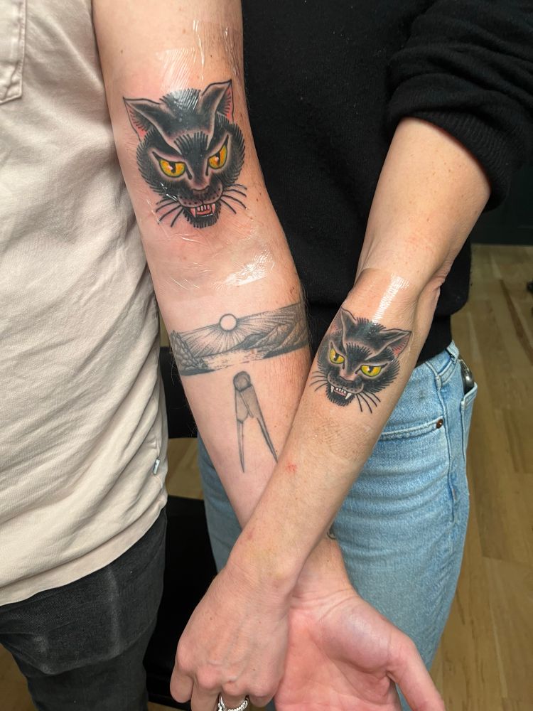 Matching memorial black cat tattoos, in American traditional tattoo style. 