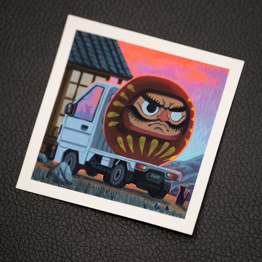Comically large daruma in the back of a kei truck during sunset.  