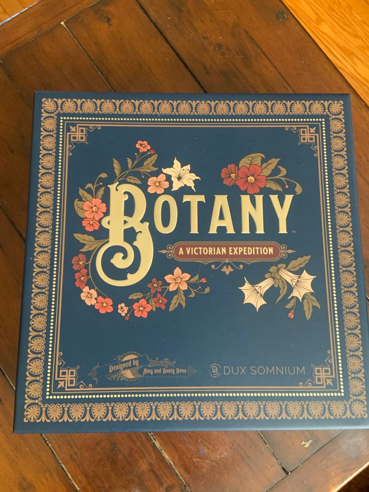 A photo of the ornately illustrated box of Botany: A Victorian Expedition, a board game about travelling the world in search of exotic plants. 