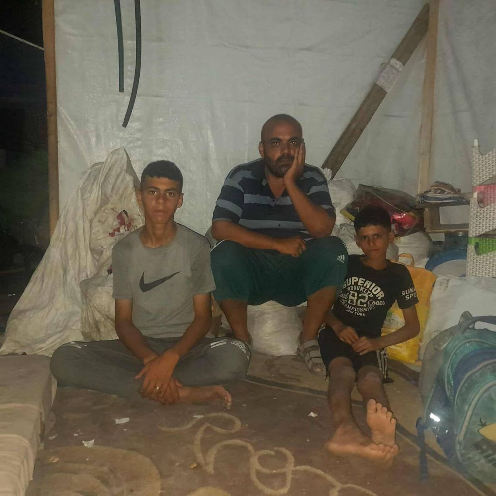 Mohammed, his dad, and his younger brother sit in their tent.