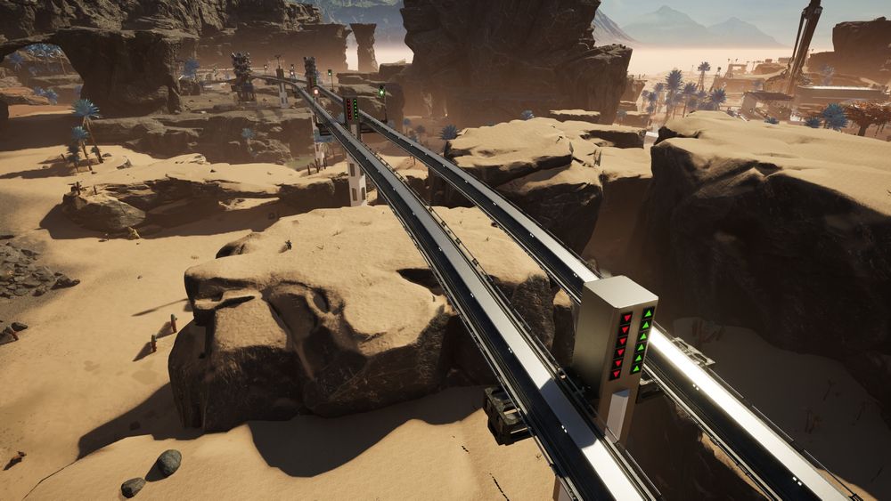 Satisfactory video game screenshot: A two-lane railway structure crosses a lumpy section of rocky desert terrain. The support pillars include green and red arrow signage to indicate direction of train travel. In the distance, the rail lines thread between two geothermal power generator units.