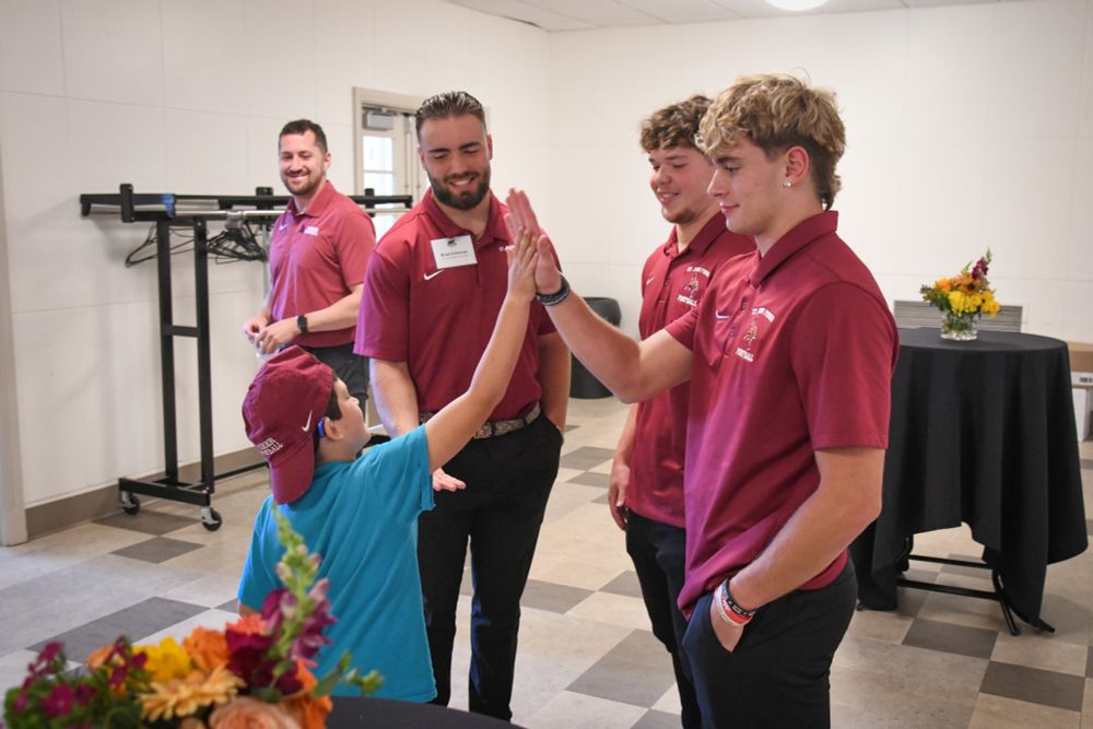 An honorary coach for Saturday's game high-fives a player from the St. John Fisher Football team.