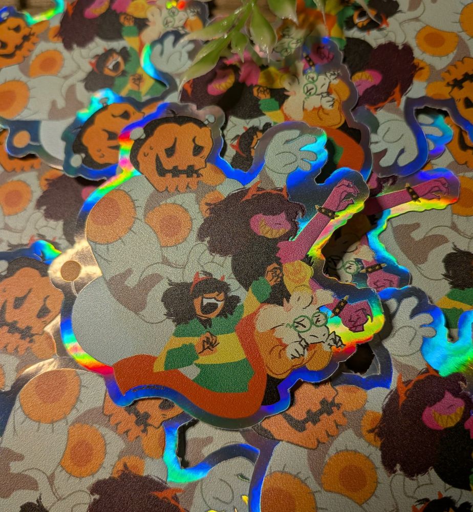 A photo of a holographic sticker featuring art I made of Jackenstein, Kris, Ralsei and Susie from Deltarune! 