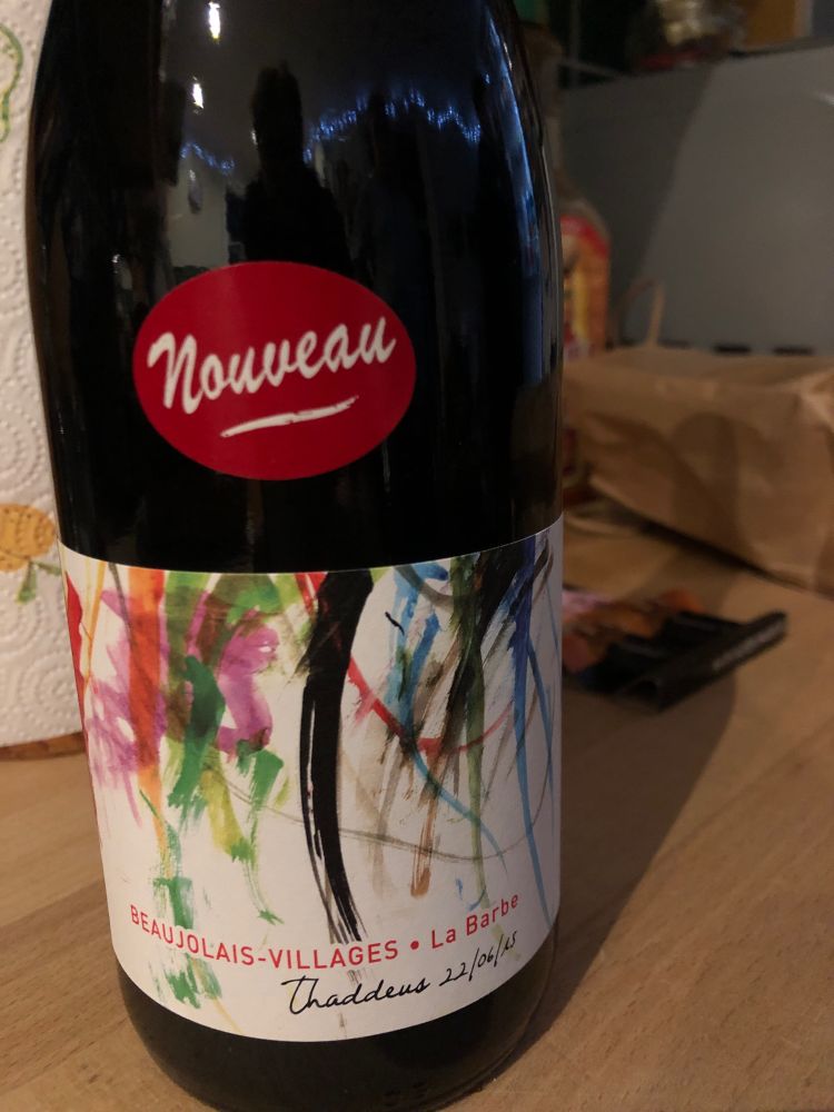 A bottle of red wine with a label 'nouveau' and an abstract art kind of colourful label