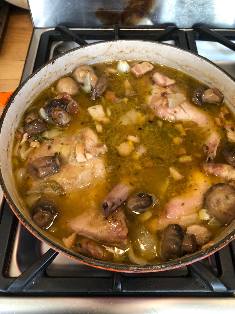 A casserole containing joints of rabbit, mushrooms, onions.