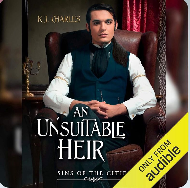 An audiobook cover. KJ Charles. An Unsuitable Heir. Sins of the Cities. Image: a white man with dark hair and sideburns is wearing formal dark green waistcoat and cravat over a white shirt, sitting in a leather armchair with his legs crossed.