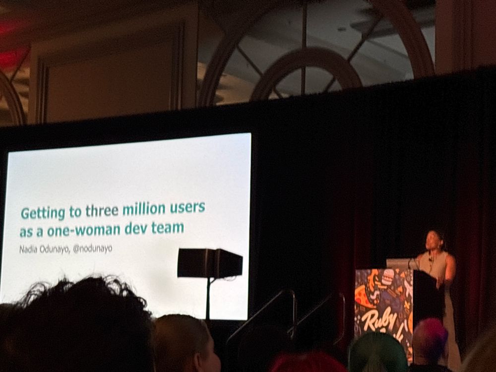 Nadia stands at the lectern in front of a slide that says “Getting to three million users as a one-woman dev team”