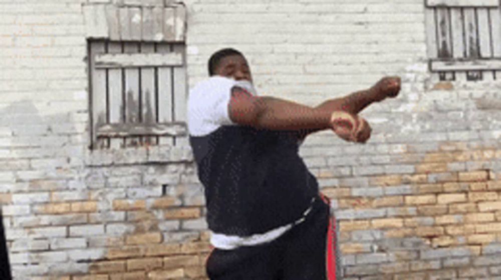 a man is standing in front of a brick wall and throwing a ball