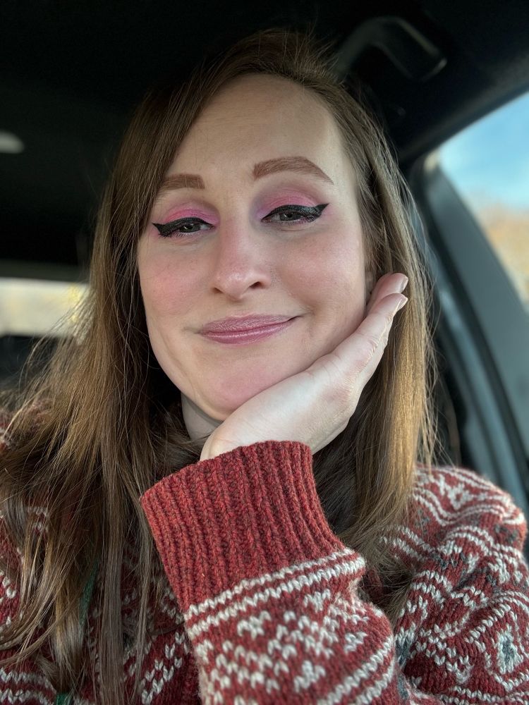 Jolene’s selfie. She has pink makeup on and a red and white coat. She’s sitting in her car