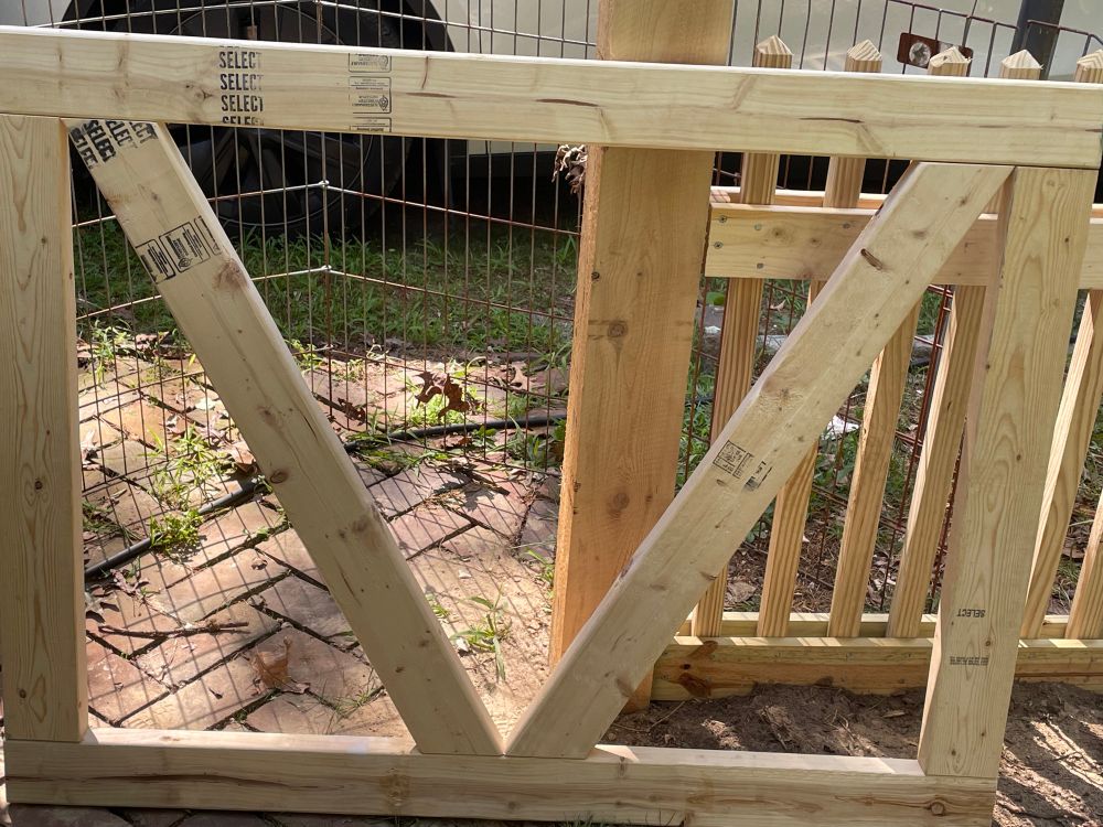A rectangular wooden gate with V shaped support pieces. 