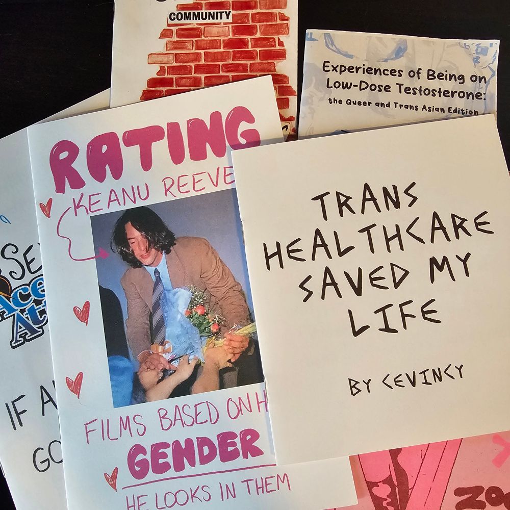 Spread of zines, of which the following titles are discernable:

Rating Keanu Reeves Films Bassed on How Gender He Looks in Them

Trans Healthcare Saved My Life by Cevincy

Experiences of Being on Low-Dose Testosterone, the Queer and Trans Asian Editon

And many others. 