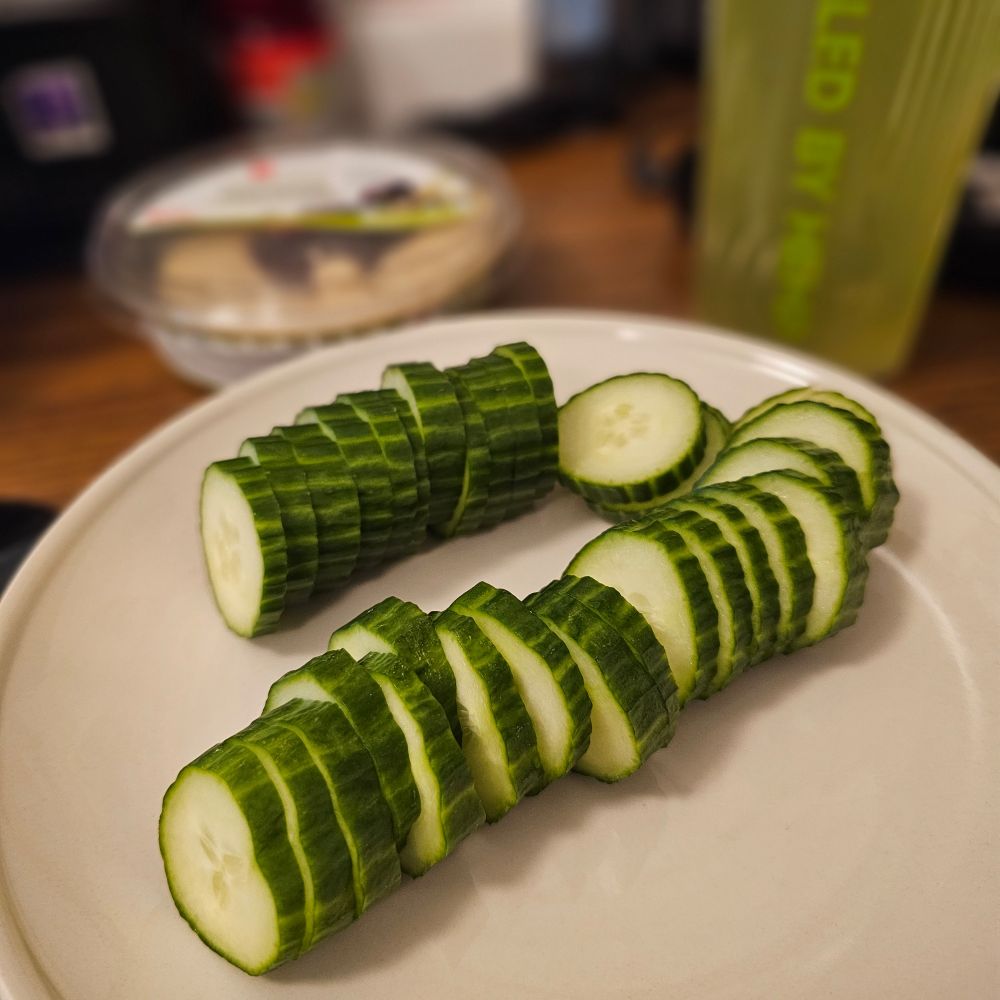 Sliced cucumber about to be consumed with olive tapenade hummus. 