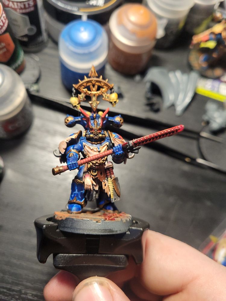 A Warhammer 40,000 Night Lord model seen from the front. He's wearing an apron of flayed skin, each panel painted a different tone, and wielding a bloody chain glaive 