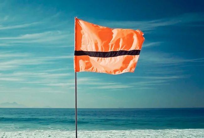 The Refugee Nation flag - an orange flag with a black stripe just above the bottom third - reminiscent of an orange life vest with a black strap