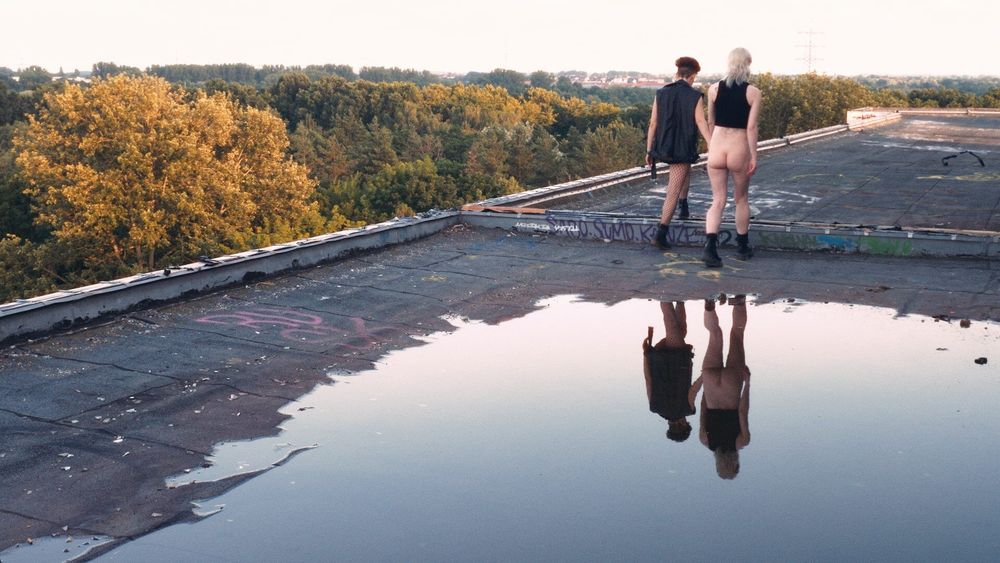 Two queer people on a roof holding hands