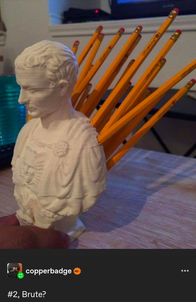 A pencil holder in the shape of a bust of Caesar, with the pencils sticking out of its back. A comment under the photo says "#2, Brute?"