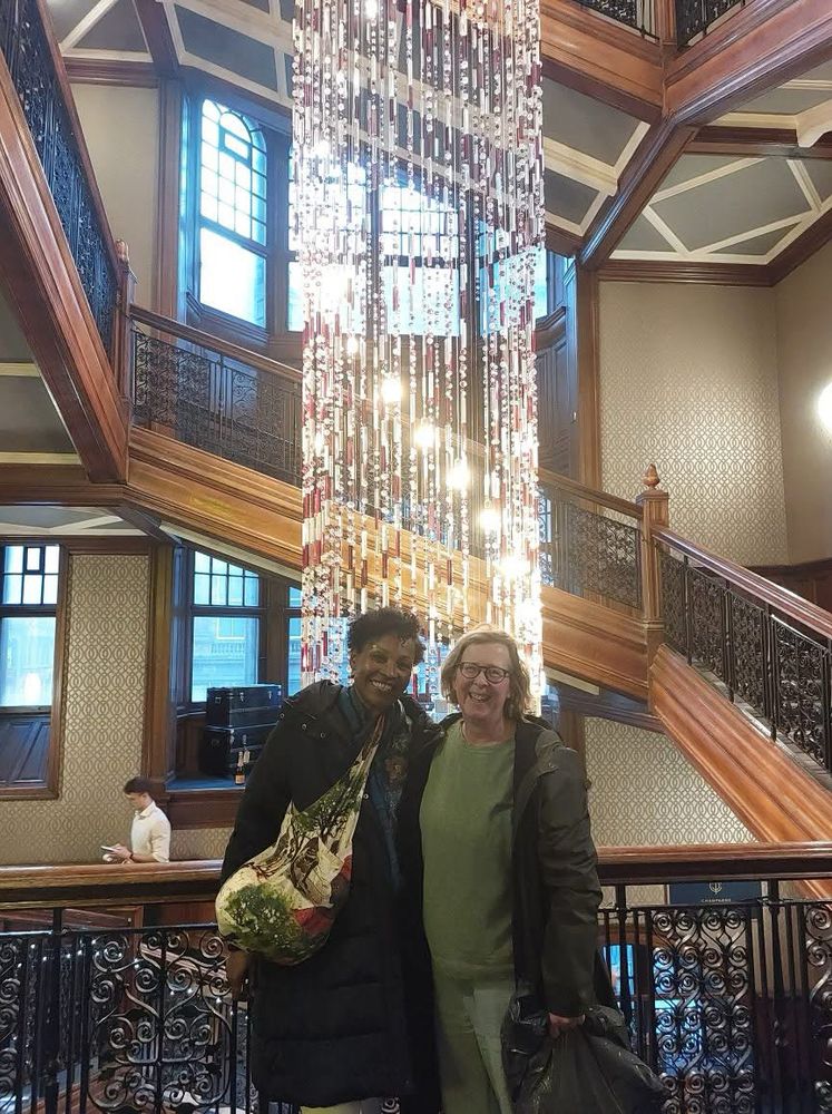 Two women standing in front of a chandelier 
