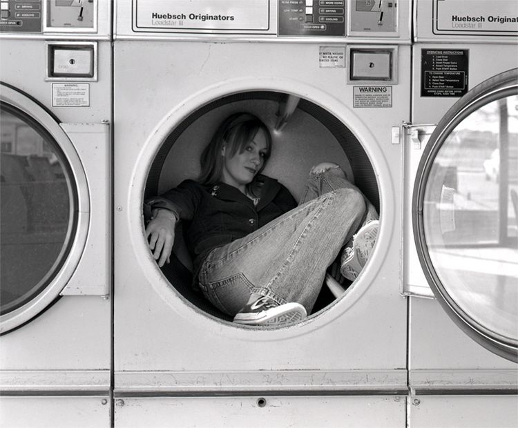 my art school self wearing jeans and chucks, sitting comfortably in an industrial dryer