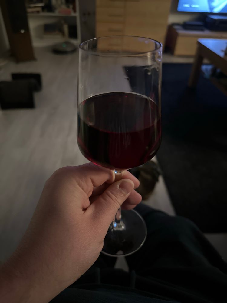 Eine Hand hält ein Riesling-Glas mit Rotwein.