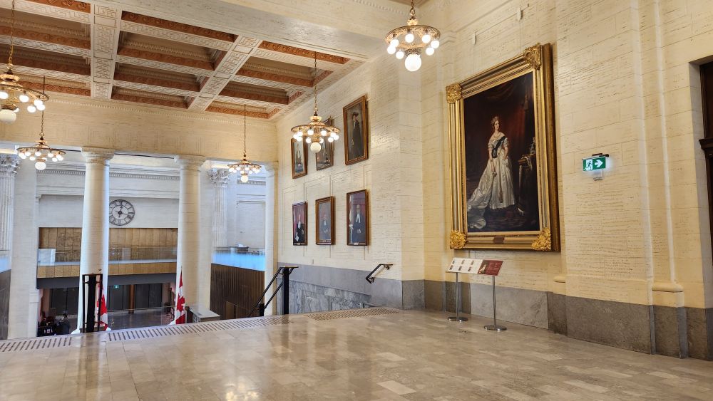 Inside the lobby of the Senate of Canada Building, with a large portrait of Queen Victoria on the wall.