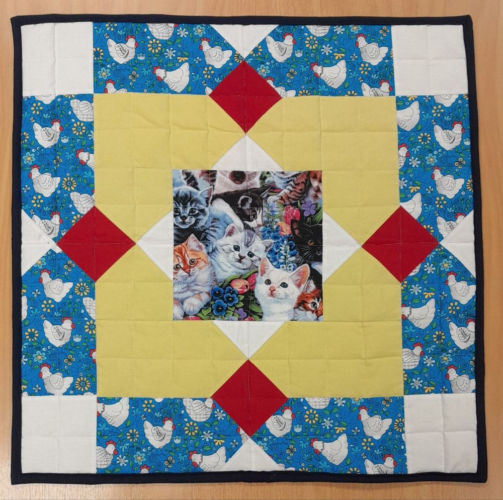 Mini quilt featuring panels of white chickens on blue BG, lemon yellow, red accent diamonds and white corners, with a central panel of kittens.