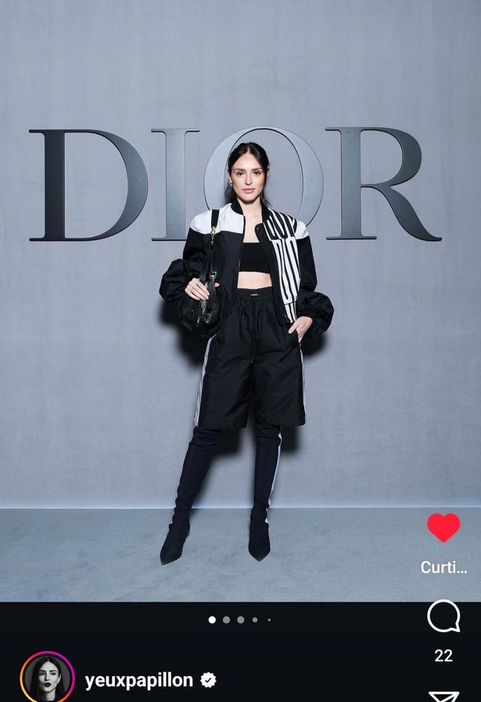 Isabelle Drummond vestindo um conjunto Dior preto com detalhes brancos (jaqueta, bermuda, top cropped e bota cano longo)