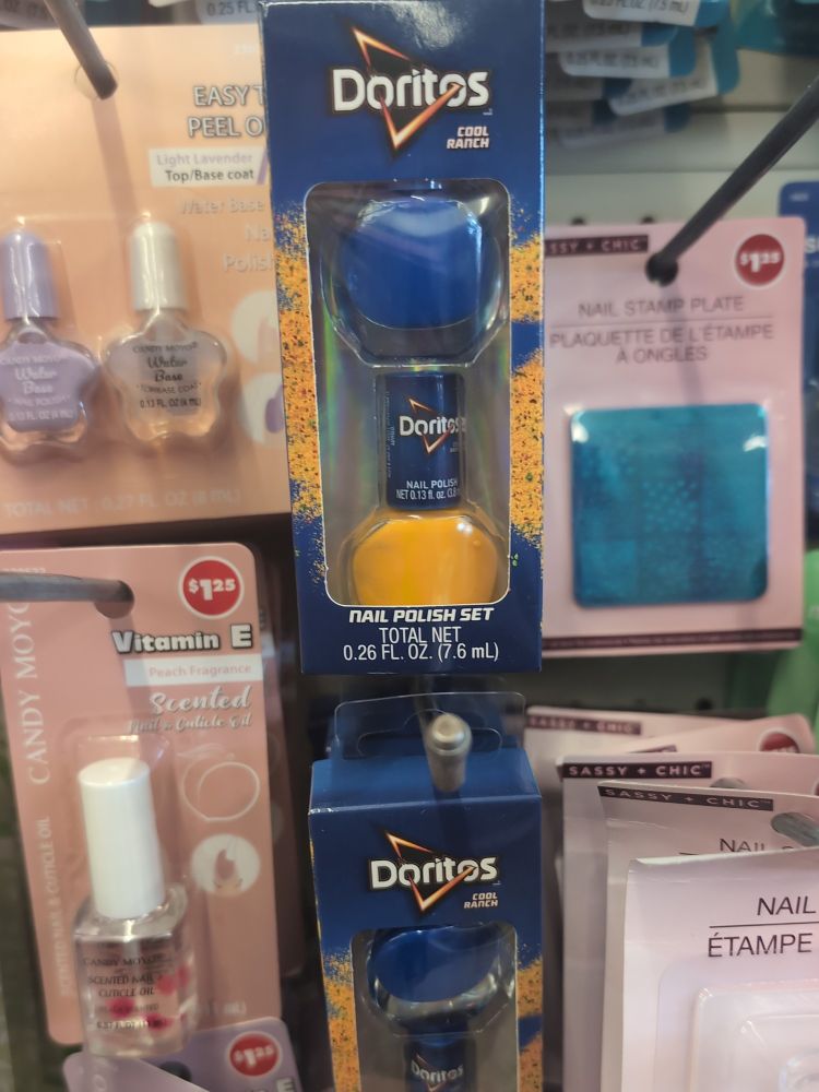 A shop rack with various bottles of nail polish. In the middle of the image are two pegboard rails of packaged nail polish labelled: Doritos Cool Ranch Nail Polish Set. The package gas two bottles of nail polish in it: one bottle is dark blue, the other is a nacho cheese kind of yellow. 