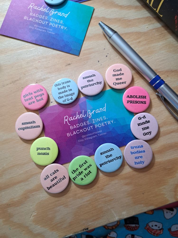 Collection of colourful queer badges surrounding a business card
