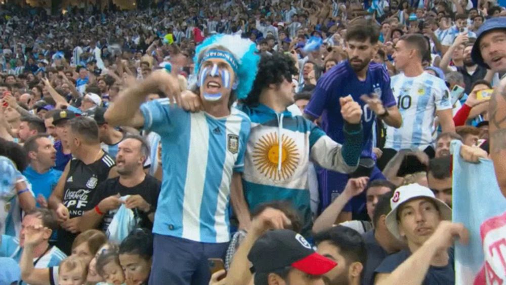 a man with argentina painted on his face stands in a crowd of people