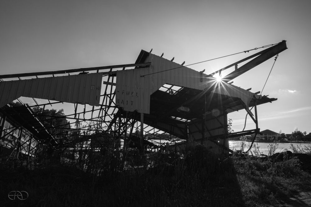A derelict dilapidated industrial building in Jean Lafitte, Louisiana stands by the bayou, leaning and a broken shelf of its former self.