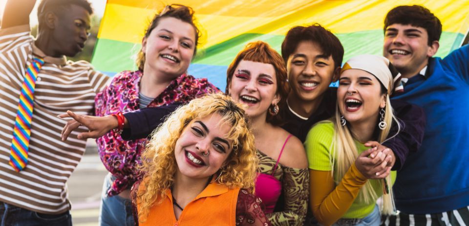 Late adolescents smiling and laughing at a Pride parade.