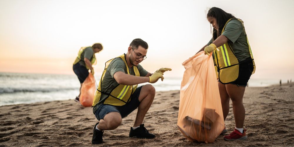 Adolescents participating in climate action by cleaning up trash on a beach. 