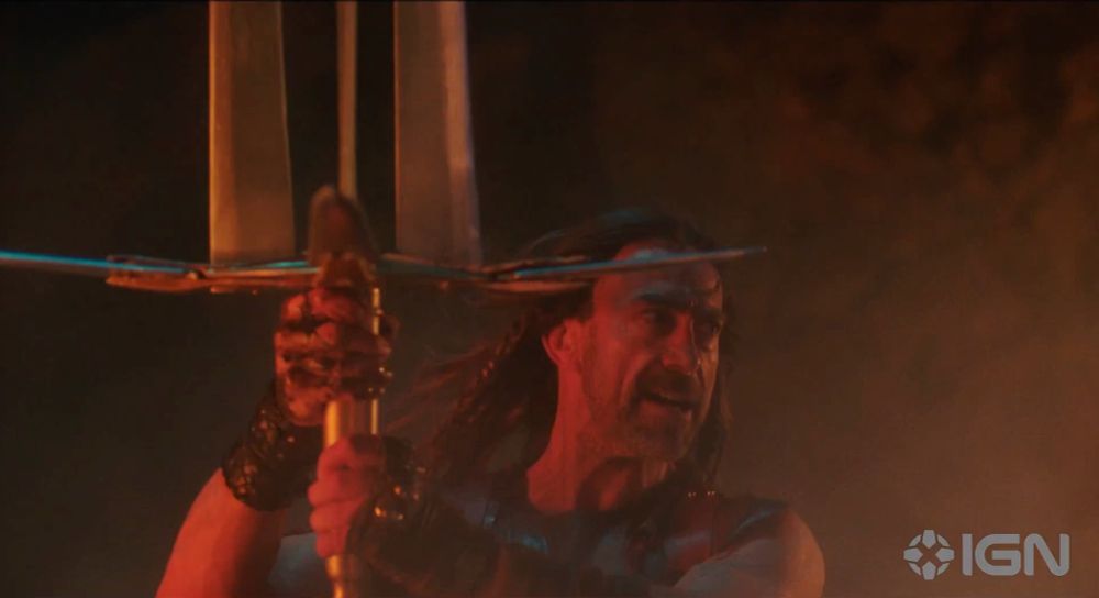 Daniel Bernhardt holding up a gigantic sword with three blades arranged in a triangle pattern on the hilt 