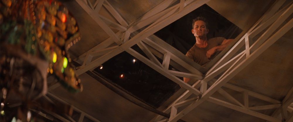 Kurt Russell's Todd, with a crewcut and mud-colored shirt, observing the party from a skylight above  
